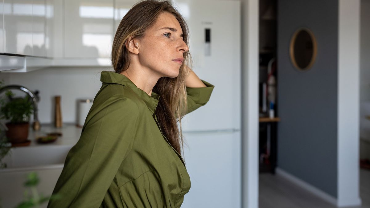 Žena protahující se u okna při ranním slunci