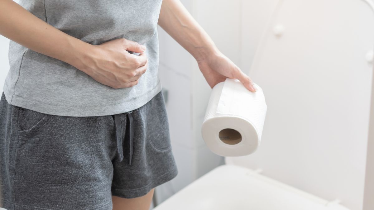 Žena s bolestmi břicha drží ruce na břiše