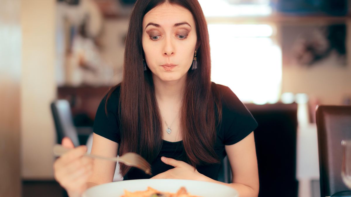 Žena pociťující únavu po obědě u pracovního stolu