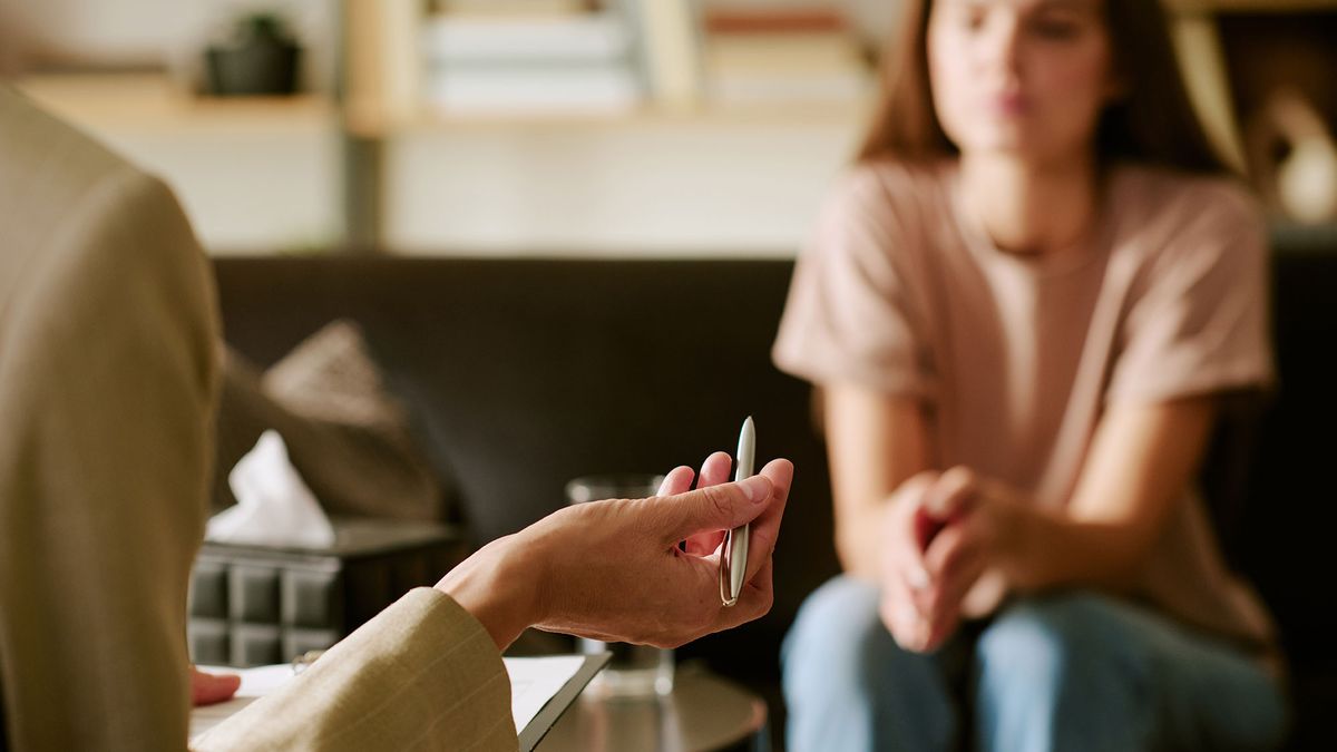 Zamyšlená žena sedí u okna a přemýšlí o svých emocích