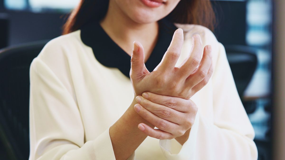 Žena si drží bolestivé zápěstí u počítače