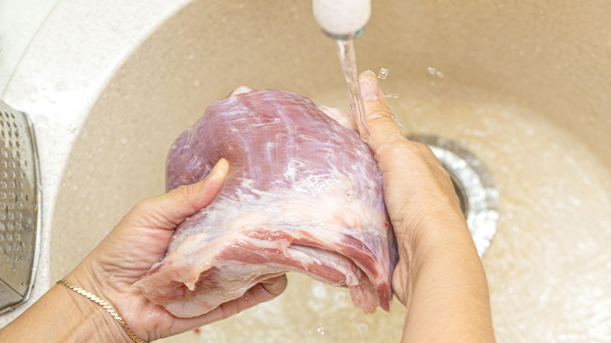 Syrové maso pod tekoucí vodou v kuchyňském dřezu